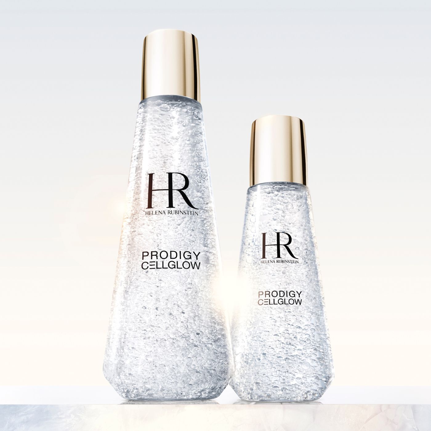 Helena Rubinstein Prodigy Cellglow: de essentie van geregenereerde huid. Twee kristalzuivere flacons, hun fijne bubbels weerspiegelen het licht, beloven een wedergeboorte van uitstraling en vitaliteit. De kunst van licht op de huid.