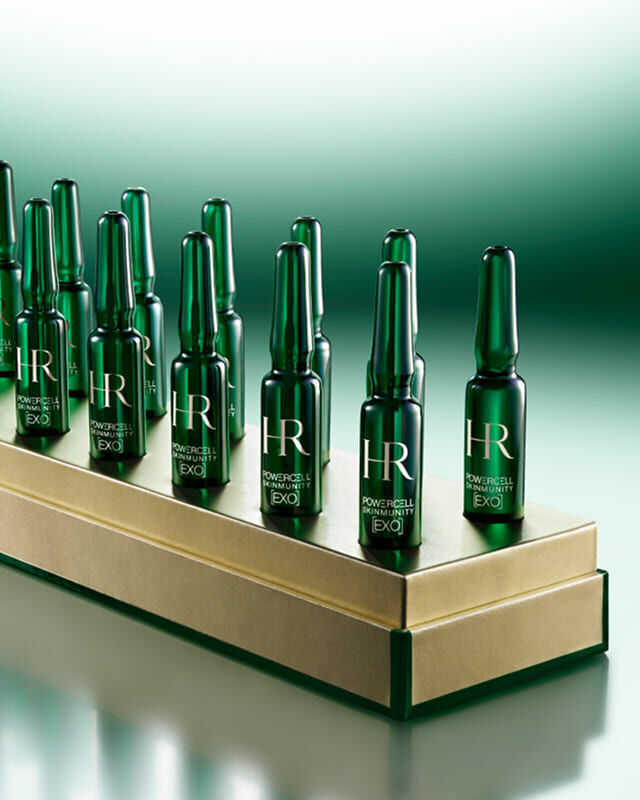 4 groene Powercell Skinmunity EXO-ampullen in eenmalige dosering op een luxe gouden voetstuk.