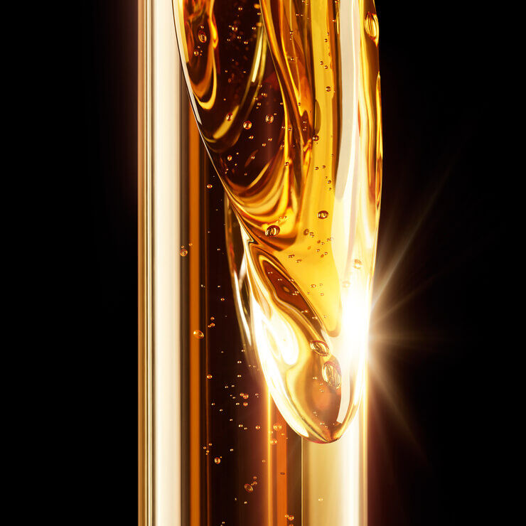 Close-up of shimmering golden liquid with bubbles, reflecting light against a dark background.