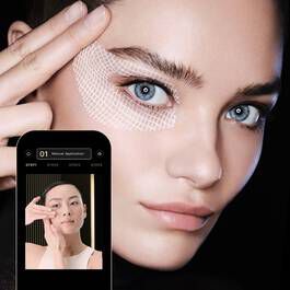 Close-up van een vrouw met nadruk op haar ogen, terwijl ze een app op haar smartphone gebruikt voor huidverzorging.